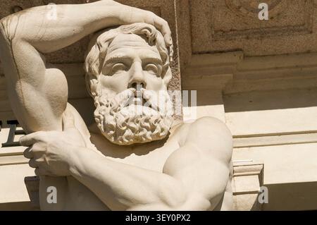 etailed close up view of the carved stone face, beard and muscular arm of the historic Omenoni male atlantes statue at Grand Palace in Lugano. Stock Photo