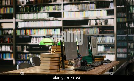 Computer monitors with chatbot, video streaming and blue screen in library desk workspace, data automation and abstract display background. Wooden table with stack of books. Stock Photo