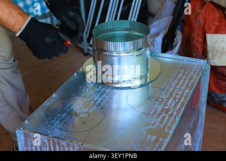 Plumbing builder works on HVAC vent metal device using tools during duct assemble Stock Photo