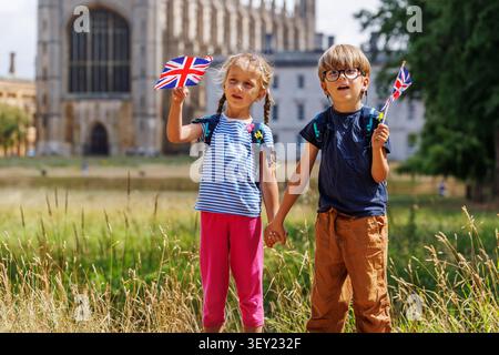 Kids wave British flags in front of historic university campus Stock Photo