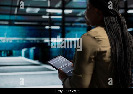 System operator uses a digital tablet in a data center to support failure detection and reliable server workflows. Stock Photo