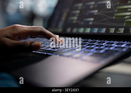Data center programmer uses a laptop computer in a data center to manage AI systems and optimize server infrastructure. Stock Photo
