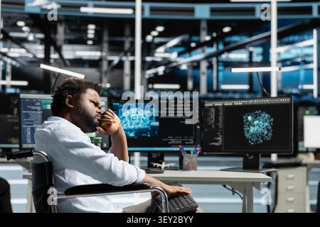 Worker with disability in a wheelchair uses deep learning algorithms in an inclusive server hub to analyze datasets and recognize patterns. Stock Photo