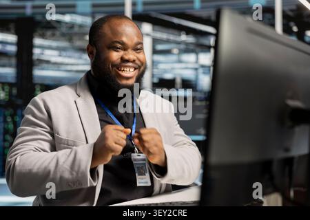 Smiling system administrator uses a clipboard to review server infrastructure, diagnostics and AI technology in a data center. Stock Photo