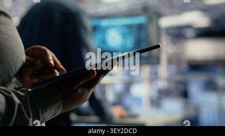 Software development team uses a tablet in a server room to review test results and confirm reliable system operation. Stock Photo