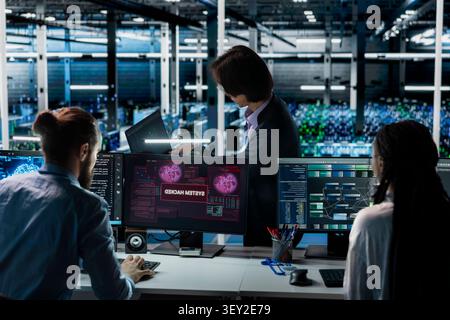 Programming team members improve security systems in a server room with machine learning to help prevent breaches. Stock Photo