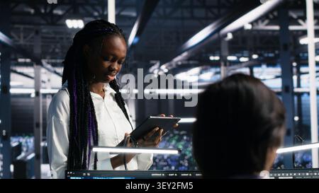 IT colleagues collaborate in a data center while reviewing AI diagnostics and infrastructure performance. Stock Photo