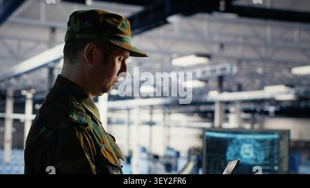 Military IT specialist reviews reconnaissance information with AI software in a server room environment. Stock Photo
