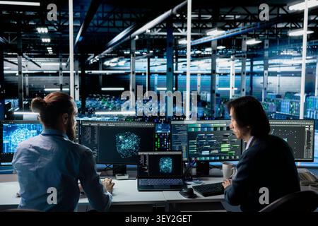 Team of engineers collaborating in high tech server room, enhancing hardware for AI tasks, increasing workloads. Stock Photo