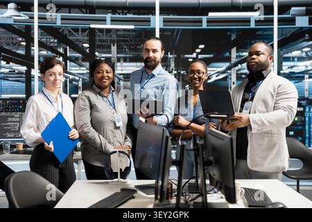 Friendly computing facility IT technician inspecting equipment, doing maintenance tasks. Stock Photo