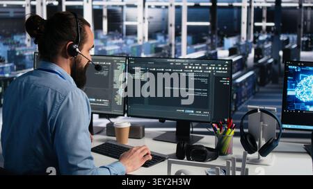 Engineer wears a headset in a server room, using artificial intelligence troubleshooting to assist users. Stock Photo