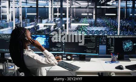 System administrator wears a headset in a server farm, using artificial intelligence troubleshooting to assist users. Stock Photo