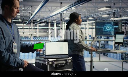 Data center worker uses an isolated screen smartphone in a server room for editable AI infrastructure review. Stock Photo