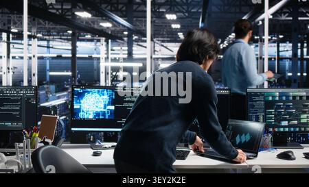 Technician programs on a computer workstation in a data center with generative AI assistance. Stock Photo