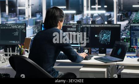 Data center technician uses laptop-based deep learning tools in a server room to improve AI operations and system efficiency. Stock Photo