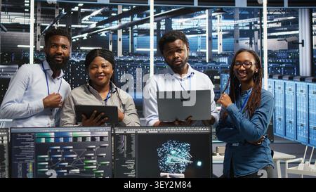 Friendly data infrastructure center specialists collaborating in data infrastructure center. Stock Photo