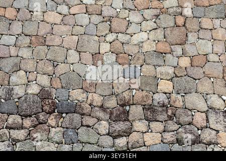 textured stone wall, background with shades of beige to brown, rounded rough stones in a seamless wall Stock Photo