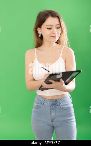 European woman using tablet and stylus on green background Stock Photo