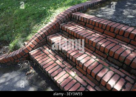 sun-dappled red brick steps beside landscaped lawn (close-up) Stock Photo