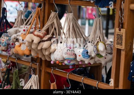 Chiang Mai, Thailand - 27 May 2026 : Handmade smiling cat face fabric keychain doll hanging among plush animal charms Stock Photo