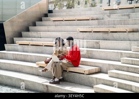 Nerdy african american man student helping black female friend with studies, explaining work process Stock Photo