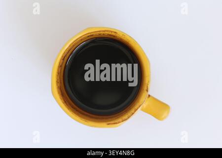 Top View Of Black Coffee In Yellow Mug On White Background Rustic Stained Rim Stock Photo