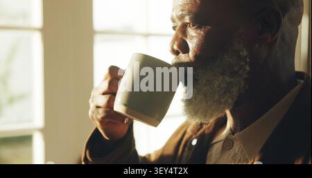 Senior, man and drinking coffee in home with reflection, perspective and calm weekend in retirement. Elderly, black person relax and thinking in Stock Photo