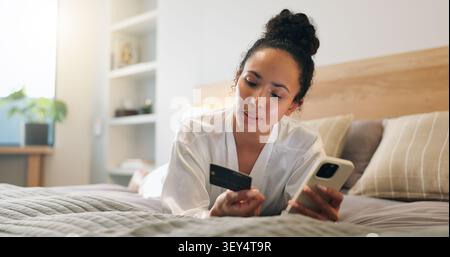 Credit card, phone and woman in bedroom for online shopping, ecommerce or purchase on mobile app. Debit, cellphone and person on bed for order on Stock Photo