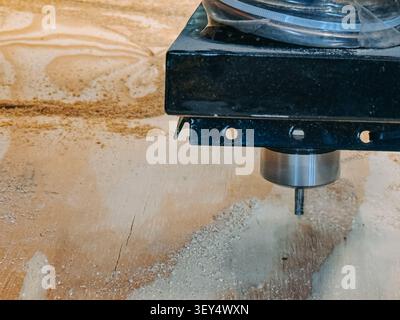 Close-up of a CNC router spindle machining a plywood sheet with a precision cutting bit. Ideal for themes of automated woodworking, industrial manufac Stock Photo