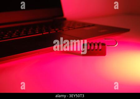 Unlocked combination padlock resting beside a laptop, symbolizing a data breach or unprotected data Stock Photo