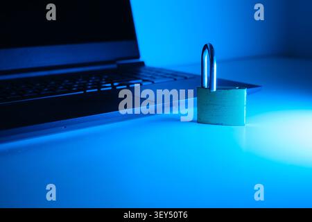Laptop keyboard with an open padlock symbolizing online data protection under blue light Stock Photo