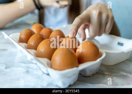 Chicken eggs in carton box on wooden table. an egg frying pan on the blurred background Stock Photo