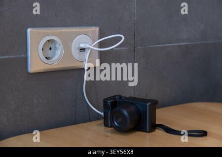 Compact camera connected to USB power outlet. Equipment maintenance and reliable power management Stock Photo
