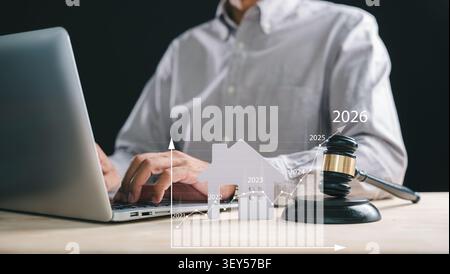 Person works on laptop, foreclosure house property law concept with gavel and rising graph illustrates estate mortgage legal trends for bankruptcy or Stock Photo