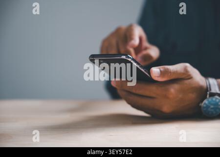 Close-up of hands holding a smartphone with a blurred background and a watch. Stock Photo