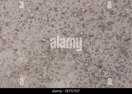 A close-up view of dry, sandy ground with scattered small stones and reddish pebbles. The texture is rough and natural, suitable for background or env Stock Photo