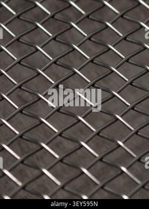 Macro view of interlaced steel wires forming repeating lattice texture, with soft reflections and shallow depth of field. Abstract industrial backgrou Stock Photo