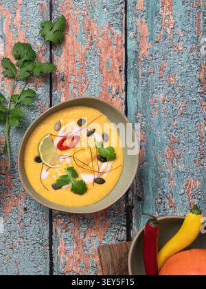 Close top view of creamy pumpkin soup garnished with chili coriander and citrus accents Stock Photo