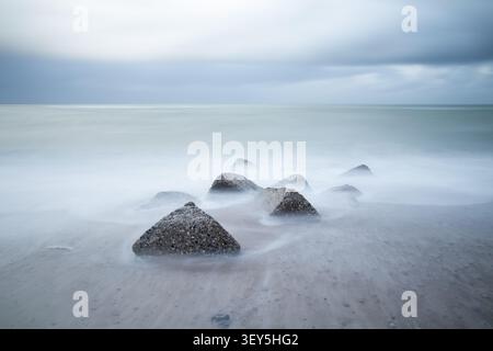 long exposure photograph captures concrete stones out in the ocean, creating calm soft lighted nature background Stock Photo