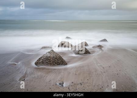 long exposure photograph captures concrete stones out in the ocean, creating calm soft lighted nature background Stock Photo