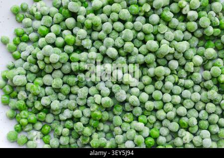 Background Green frozen peas on a white plate. Healthy food concept. Frozen legumes. Horizontal orientation. Top view. Stock Photo