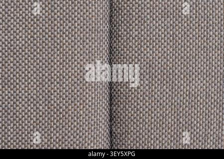 Horizontal close up detailed shot of a grey upholstery burlap fabric texture with a central seam line showing a heavy duty durable woven fiber structu Stock Photo