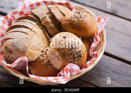 Artisan Sourdough Bread and Seeded Rolls Served in Basket on Wooden Table Stock Photo