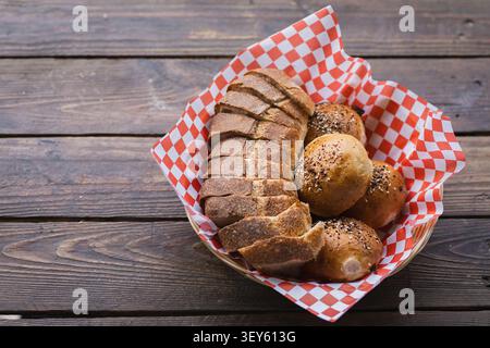 Artisan Sourdough Bread and Seeded Rolls Served in Basket on Wooden Table Stock Photo