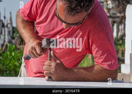 Stone mason meticulously working on a stone tile installation. This close-up shot captures the skilled craftsmanship involved in this traditional buil Stock Photo