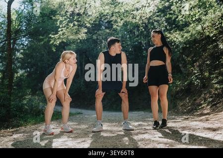 Friends taking a break on a forest trail during outdoor fitness workout together Stock Photo