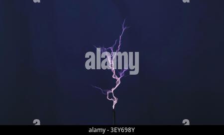 Electrical discharge creating a branching lightning bolt on a dark blue background Stock Photo