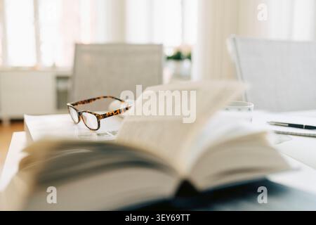 Eyeglasses resting on open book on desk in retirement Stock Photo