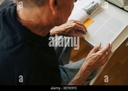 Over the shoulder view of elderly man reading book in retirement home Stock Photo