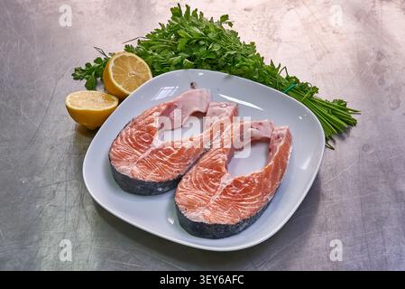 two slices of salmon on a white plate with parsley and lemon Stock Photo
